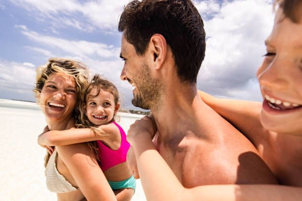 istock Happy family having fun while piggybacking on the beach. 1372714570