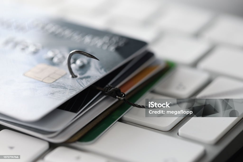 Fishing hook with credit cards on keyboard closeup Fishing hook with credit cards on keyboard closeup. Cybercrime on internet concept Phishing Stock Photo