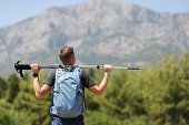 Man stands on mountain and holds Nordic walking poles