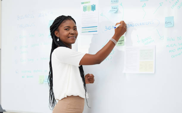снимок молодой бизнесвумен, пишущей на доске за работой - с днем учителя стоковые фото и изображения