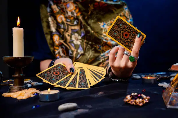 The fortune teller holds a fan of cards Tarot in her hands, and show one card. Close-up. The concept of divination, magic and esotericism.