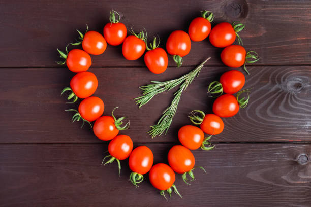 czerwony pomidor w kształcie serca na drewnianym stole. ekologiczna zdrowa żywność. składniki do gotowania.pomodoro na biurku - cherry tomato tomato sauce isolated close up zdjęcia i obrazy z banku zdjęć