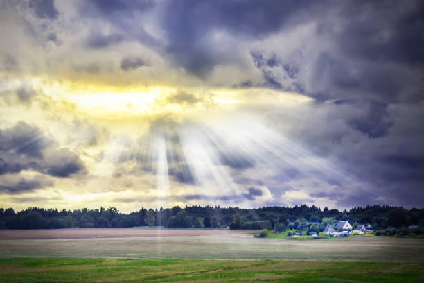 Atmospheric moment. Summer sunset landscape with dramatic sky, natural background, dark storm clouds. Changeable weather. In the distance, on the edge of the field, a lonely house.