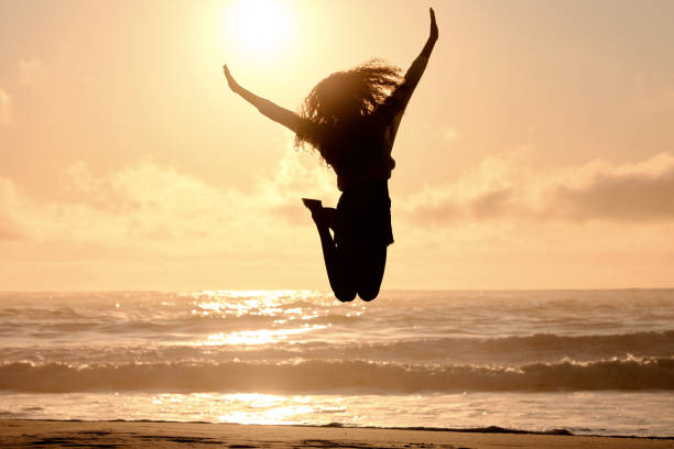 photo d’une femme méconnaissable sautant pour célébrer à la plage - joie photos et images de collection