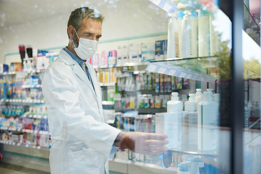 A pharmacist arranges products on a shelf.
