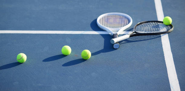 shot of two tennis rackets and tennis balls on a court during the day - tennis court tennis ball racket imagens e fotografias de stock