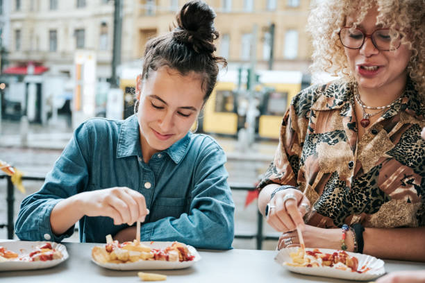 zwei teenager-mädchen essen currywurst mit pommes frites in berlin - currywurst stock-fotos und bilder