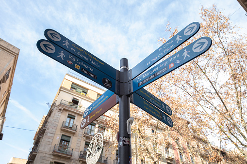 Barcelona, Spain - Jan 08, 2022: A tourist information and help sign, with several signs and arrows pointing the direction to different famous places in the city