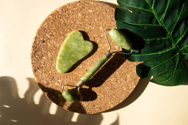 istock Jade Gua sha scraper and face roller massager on a cork round stand with a monstera leaf 1372731443