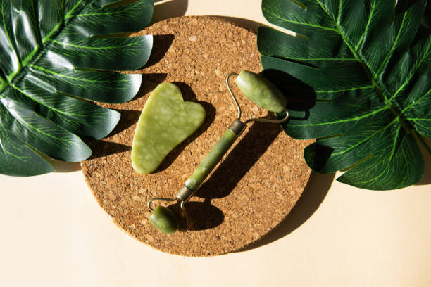 istock Jade Gua sha scraper and face roller massager on a cork round stand with a monstera leaf 1372731641