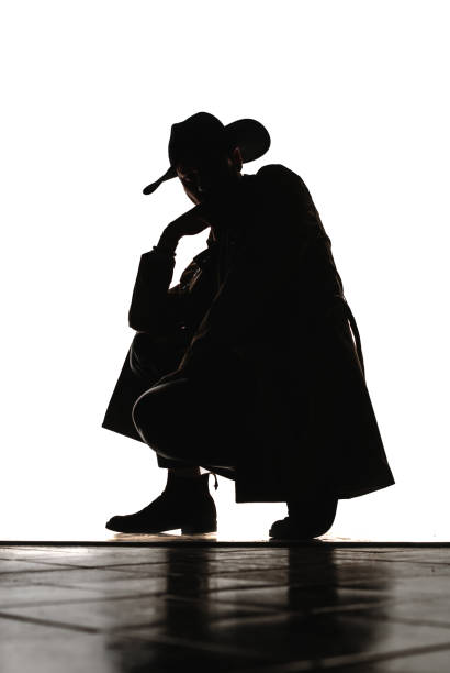 Attractive young stylish man posing in beige long coat and black hat