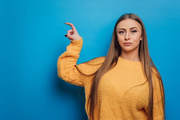 istock Woman holding something with her hand and showing it to camera while standing over an isolated background. 1372733344