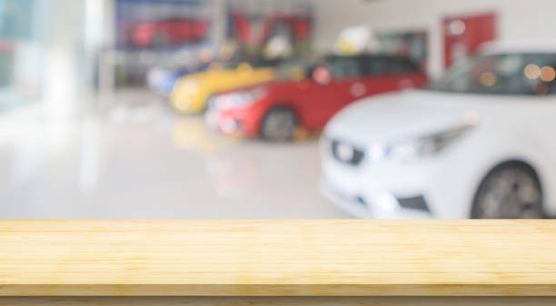 Empty wood table top with cars in showroom blurred defocused background stock photo
