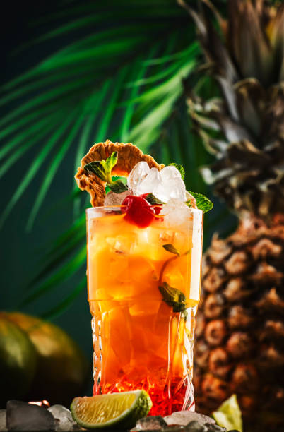 istock Alcoholic cocktail with vodka, pineapple juice, mango, red syrup and ice. Long drink or summer cold mocktail. Tropical dark background with palm leaves and exotic fruits 1372734998
