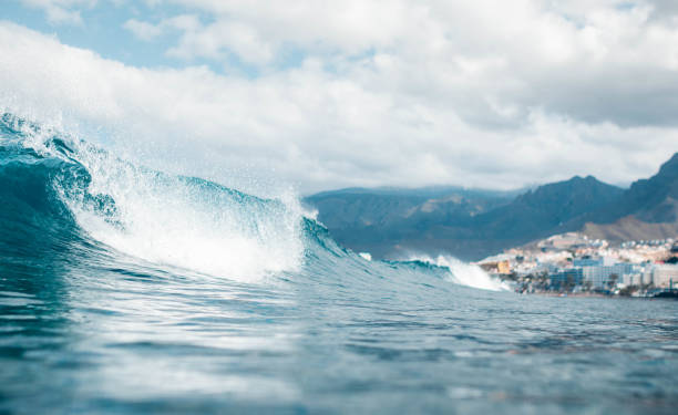 Low angle of a breaking wave on a cloudy day with buildings in the background. Playa de las Americas, Tenerife
