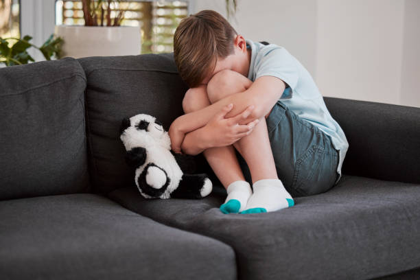 自宅のソファで自分自身を慰める小さな男の子のショット - 6歳から7歳 ストックフォトと画像