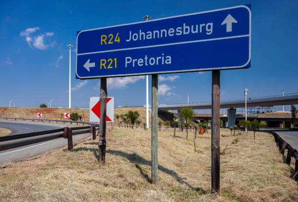 road signs indicating the direction of travel to pretoria and johannesburg at the fork in the road. - pretoria imagens e fotografias de stock