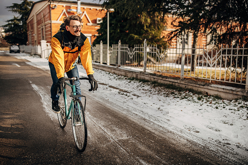 One man, male riding his bicycle to work on the city street on a winter day.