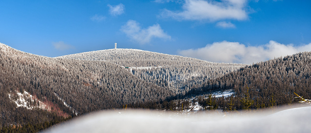 Winter landscape in the Polish mountains of the Sudetes, a view of the snow-capped mountain peaks, an observation tower on the top of Snieznik.