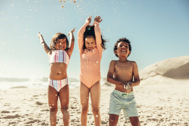 istock Happy kids throwing beach sand into the air 1372742133