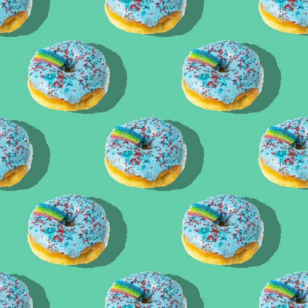 istock A repeating pattern of blue donuts with a rainbow on a green background. Flat lay 1372742518