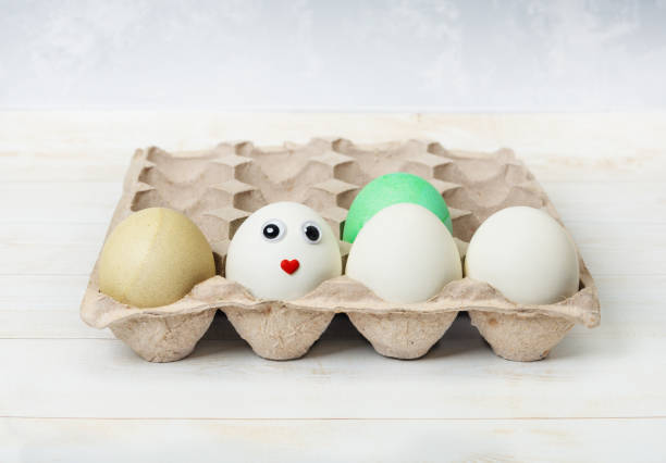 istock The egg carton contains dyed and white eggs. One egg has a cute face. Easter concept 1372743310
