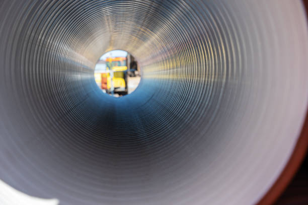 istock Inside the plastic corrugated pipe. Polypropylene pipe for laying in the ditch. Defocused image of construction equipment on the back end of the pipe. 1372743753