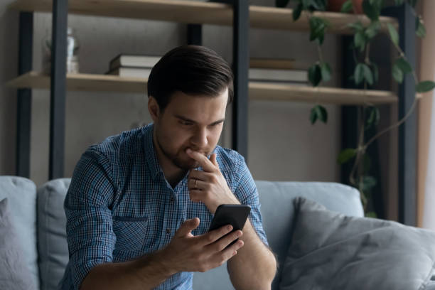 istock Thoughtful serious man touching chin, looking at smartphone screen 1372744100