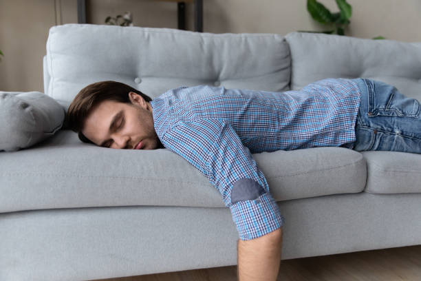 istock Exhausted man lying on comfortable couch at home, sleeping 1372744126
