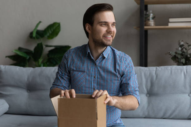 istock Overjoyed man holding cardboard box on laps, sitting on couch 1372744138