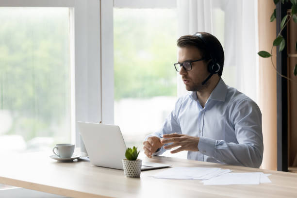 istock Confident man in wireless headset talking, using laptop, chatting online 1372744140