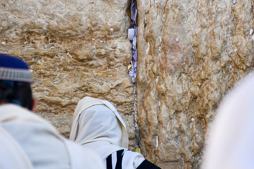 Praying at the Wailing Wall Jerusalem Israel. The Western Wall, Wailing Wall or Kotel  is located in the Old City of Jerusalem. It is a relatively small western segment of the walls surrounding the area called the Temple Mount by Jews, Christians and most Western sources, and known to Muslims as the Noble Sanctuary. 