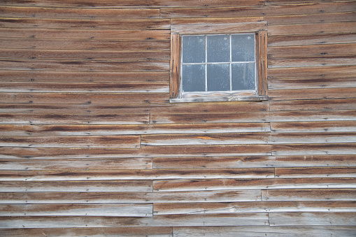 Old abandoned wooden cabin of the wild west USA in tiny town of Two Dot, Montana near the dangerous Crazy Mountains. This is in northwestern United States of America's (USA) old wild west of endless prairies, rolling hills and majestic snow capped mountains.