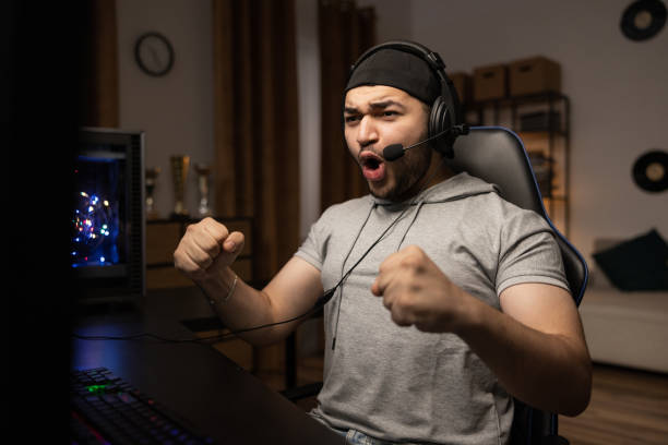 istock A professional player with a headset playing and winning a video game on his computer. Online championship in a virtual world. Clenched fists with joy at the victory shout 1372751534