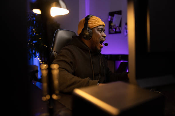 istock A professional computer player goes a round in a game. The man opens mouth in shock, surprise, can't believe his luck. The gamer has a headset and talks into the night with team members 1372751621