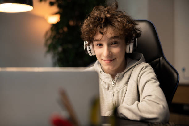 istock A young boy with curly hair is happy with remote learning. A student sits in front of a computer with wireless headphones listening to a teacher lecture. The lessons take place over the Internet 1372751721