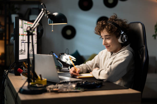 istock A child designs a building for tech class, does homework, draws with a pencil in a notebook, looks at a computer screen with graphics on. A boy's room with a desk, vinyl records on the wall 1372751746