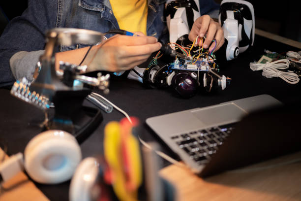 istock Desk with laptop, tools, soldering equipment. Boy fixes robot, solders cables, plays with electronics, builds toy 1372752220
