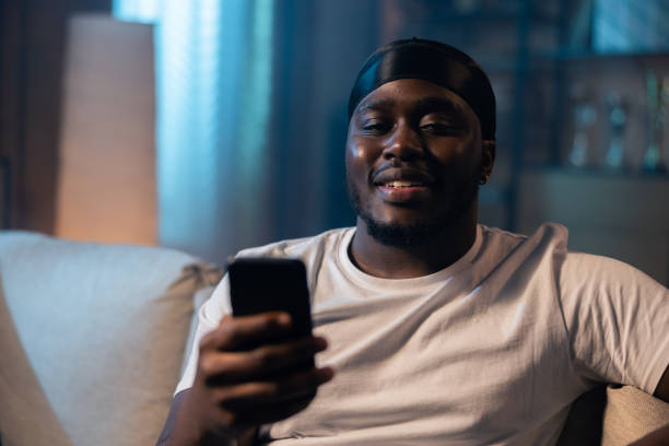 istock Man using smartphone at night browsing internet and updating social media. Young guy with beard is smiling while holding phone in hand 1372752815