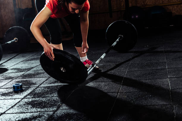 istock Woman in gym changing weights on lifting bar 1372753861