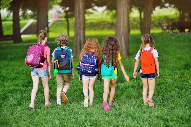 group of children with school backpacks walking hand in hand. Holidays, back to school, summer camp stock photo