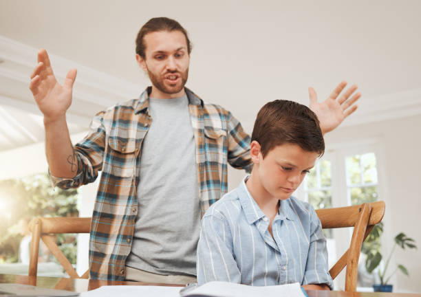 Shot of a young father looking frustrated while helping his son with homework at home I just can't win with this kid boring homework twelve stock pictures, royalty-free photos & images