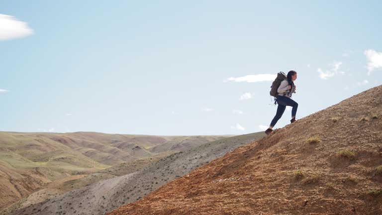 Woman climbing step by step on red mountain peak