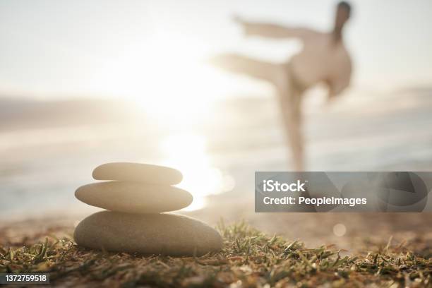 Closeup Shot Of A Stack Of Stones On The Beach With A Man Practicing Karate In The Background Stock Photo - Download Image Now