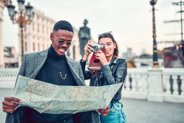 African Male Getting Photographed By Girlfriend While Examining Map During Tour Trip