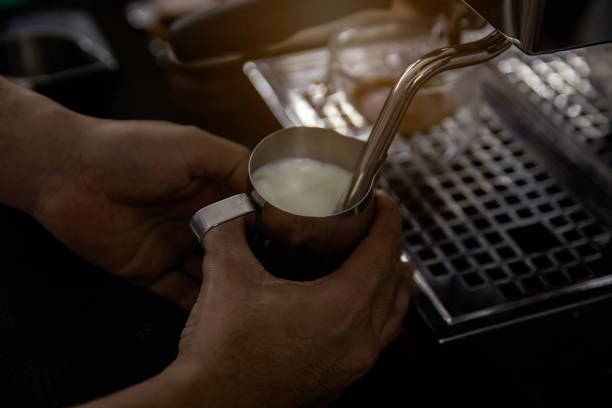 istock barista steaming stainless cup milk in coffee bar. 1372764499