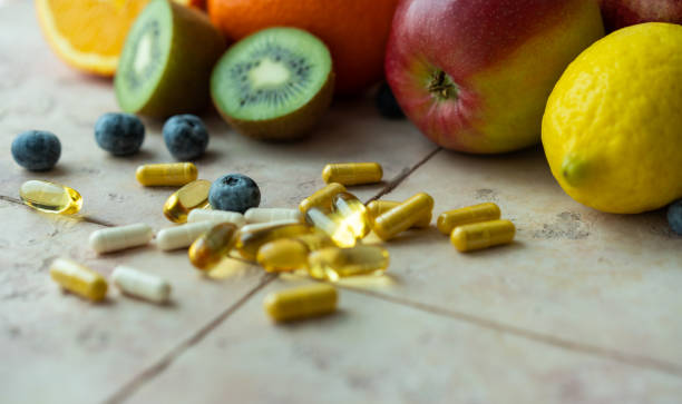 frutas naturais e cápsulas multivitamínicos. fontes naturais e sintéticas de vitaminas - vitamin pill nutritional supplement capsule antioxidant - fotografias e filmes do acervo