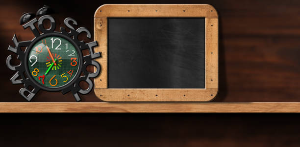Close-up of an alarm clock with text Back To School and an empty blackboard with wood frame with copy space, above a wooden shelf.\