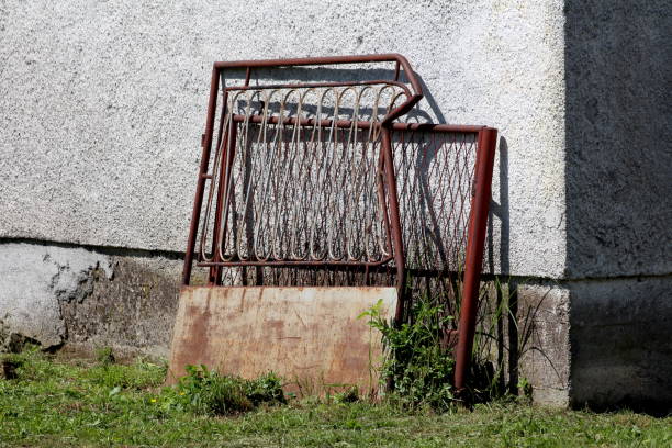 istock Broken destroyed twisted rusted metal outdoor fence doors with dilapidated white panel left next to family house wall 1372777746