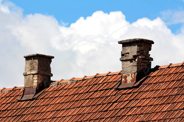 istock Two very old narrow broken red building bricks chimneys with rusted metal sheet protection on top of abandoned suburban family house 1372778116